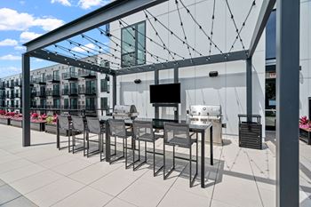 a patio with a long table and chairs under a glass roof